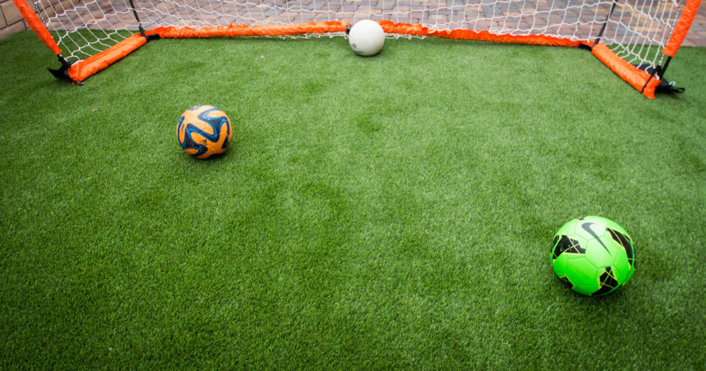 soccer ball and goal placed on artificial grass